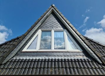 Open roof window in velux style with black roof tiles